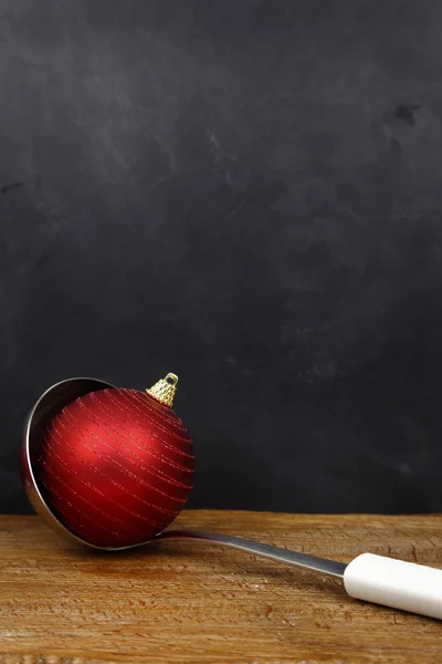 Christmas ball in a serving spoon and copy space on black background — Stock Photo, Image