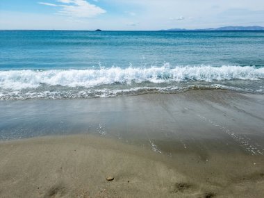 Islak kumda deniz dalgalı beyaz köpük. Boş kumlu plaj, Yunan adası Cyclades, Yunanistan. Yaz tatili şablonu, boşluk.