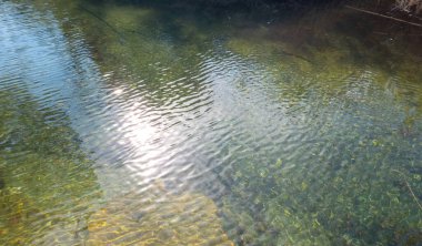 Su altında şeffaf su, turkuaz çakıl taşları arka plan, doku. Yunan adası Cyclades Yunanistan 'da taşlı sakin sığ deniz. Üst görünüm