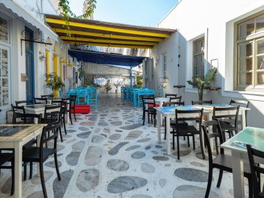 Yunan açık hava geleneksel taverna restoranı Tente adası, Chora kasabası, Cyclades Yunanistan. Parke sokağında masa ve sandalyeler
