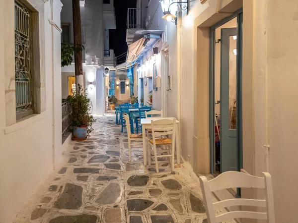 ギリシャの屋外居酒屋レストランティノス島 コラ町 キクラデスギリシャ 午後照明付きのランプポストテーブル石畳の通りの椅子 — ストック写真