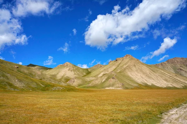 Malerische Hügel vor dem Hintergrund des farbenfrohen dunkelblauen Himmels mit Wolken in der Nähe des Kelsu-Sees — Stockfoto