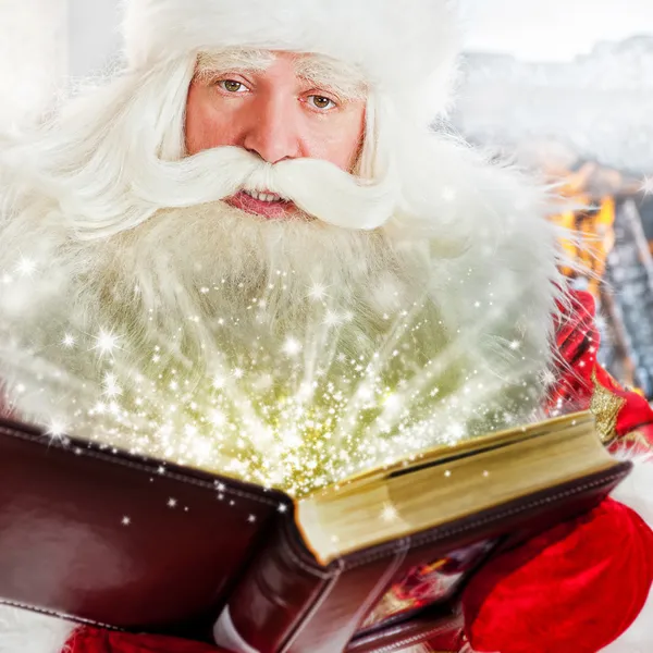 Der Weihnachtsmann sitzt am Weihnachtsbaum, am Kamin und liest ein Buh — Stockfoto