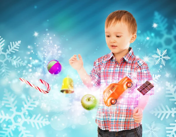 Little boy conjuring toys and confection with his hands — Stock Photo, Image