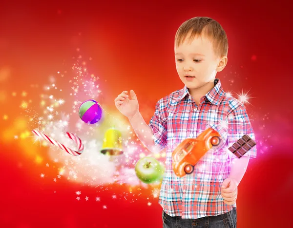 Kleiner Junge zaubert mit seinen Händen Spielzeug und Süßigkeiten — Stockfoto