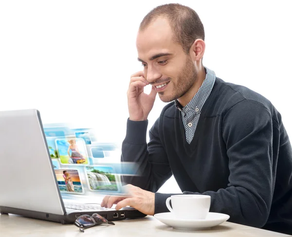 Um jovem sentado na frente de um laptop e compartilhando foto e v — Fotografia de Stock