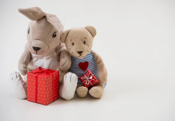 Conejo de juguete de estilo retro y oso se sientan abrazándose con cajas de regalo —  Fotos de Stock