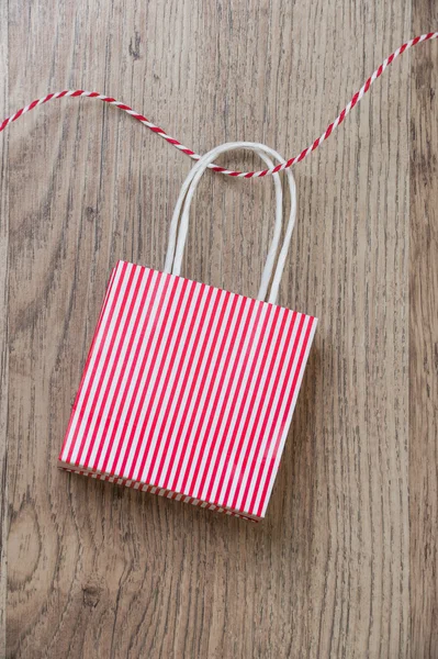 Подарочный пакет с красной лентой на деревянном фоне — стоковое фото
