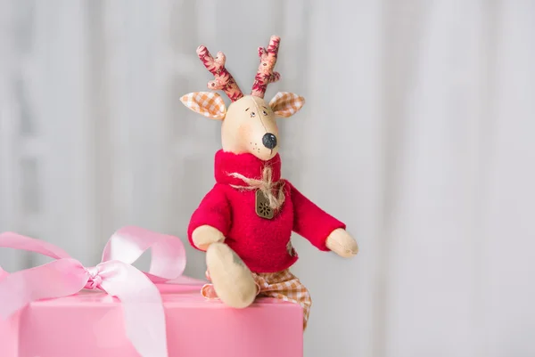 Handgemachtes Spielzeug Vintage Weihnachten Hirsch sitzt auf der rosa Geschenkbox — Stockfoto