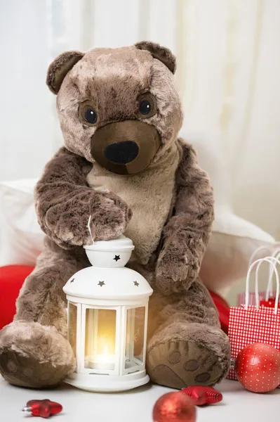 Urso de pelúcia de Natal sentado com lanterna e presentes ao redor — Fotografia de Stock