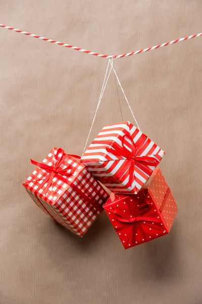 Rote Geschenkboxen, die an einem Band hängen. alter brauner Papierhintergrund — Stockfoto