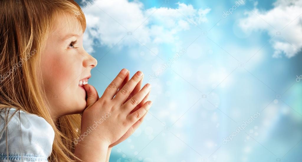 Portrait of young smiling praying girl in blue dress against sky
