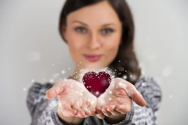 Pretty young brunette woman smiling against gray background with — Stock Photo, Image