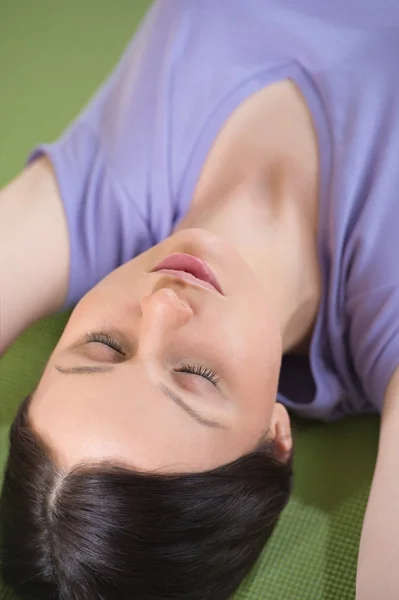 Retrato de una joven fitness acostada en una esterilla de yoga y exerci —  Fotos de Stock