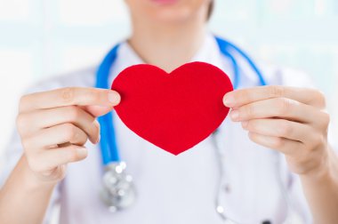 Kırmızı insan kalbinin elinde stetoskop ile kadın doktor