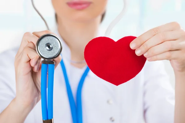 Médica com estetoscópio segurando coração humano vermelho — Fotografia de Stock