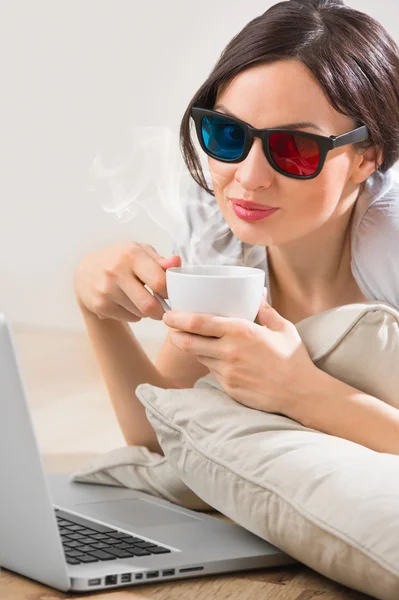 Una joven tumbada en el suelo frente a su portátil con taza — Foto de Stock