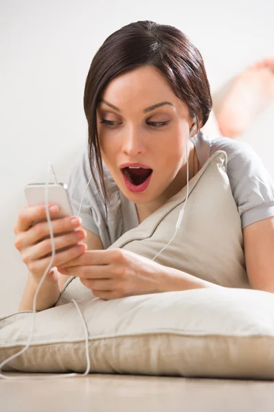 Eine junge Frau mit ihrem Handy auf dem Boden liegend — Stockfoto