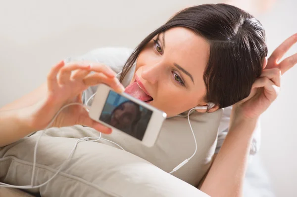 Una giovane donna sdraiata sul pavimento con il suo telefono e sparando — Foto Stock