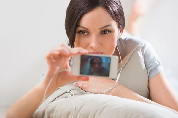 Uma jovem deitada no chão com o telefone e atirando — Fotografia de Stock