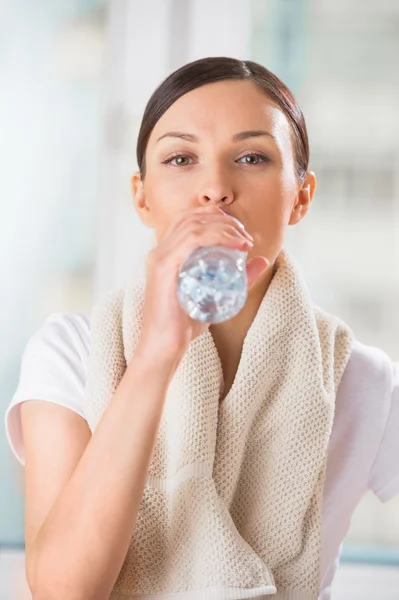 Retrato de jovem mulher bebendo água no ginásio depois de fazer exerci — Fotografia de Stock