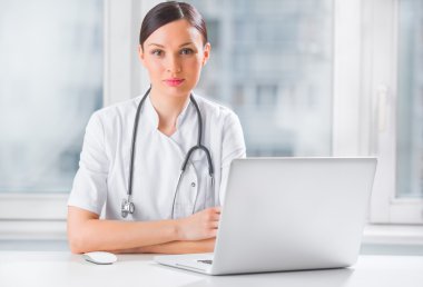 Portrait of a female doctor using her laptop computer at clinic clipart