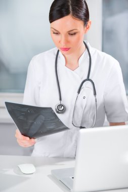 Portrait of a female doctor holding ultrasound results and using clipart