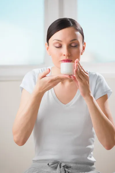 Jonge vrouw holding kopje thee of koffie thuis en ademhaling — Stockfoto