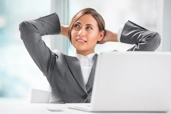 Hermosa ejecutiva femenina relajándose con las manos detrás de la cabeza — Foto de Stock