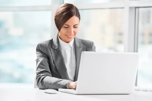 Ocupada mujer de negocios caucásica utilizando el ordenador portátil en el escritorio de oficina — Foto de Stock