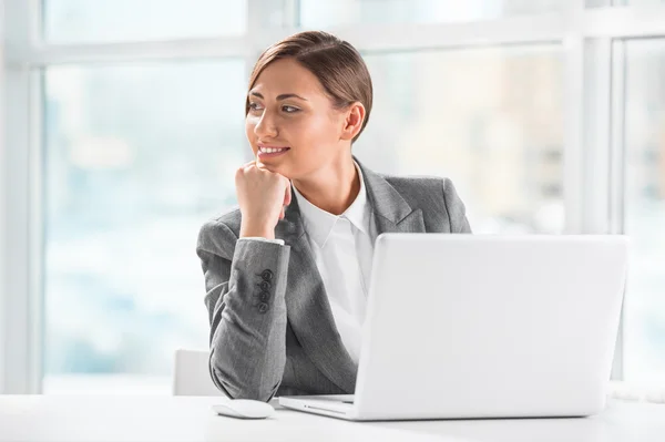 Tankeväckande affärskvinna hålla hakan samtidigt med laptop på wor — Stockfoto