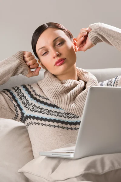 Retrato de uma jovem mulher sentada na frente de seu laptop no sofá — Fotografia de Stock