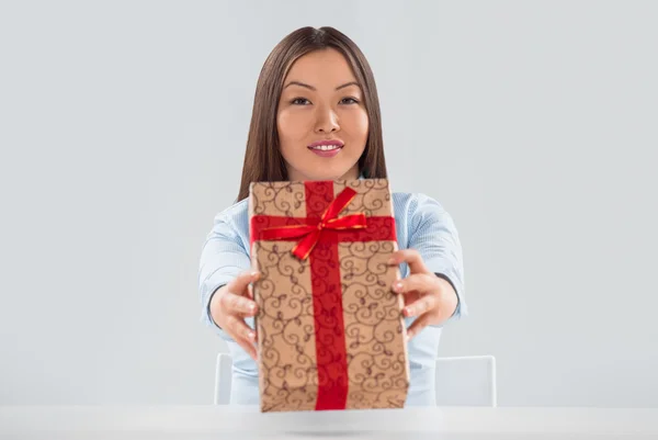 Porträt einer jungen Geschäftsfrau, die mit einem Geschenk an ihrem Schreibtisch sitzt — Stockfoto