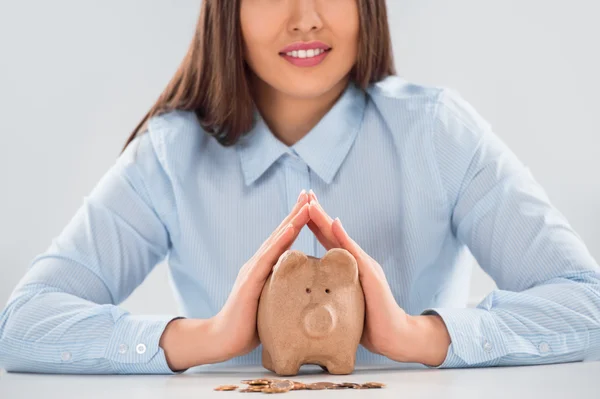 Happy business woman covering piggy bank with two hands — Stock Photo, Image