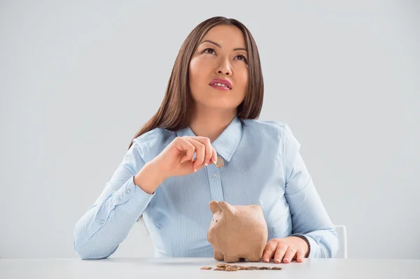 Junge glückliche Geschäftsfrau legt Geld in das Sparschwein — Stockfoto