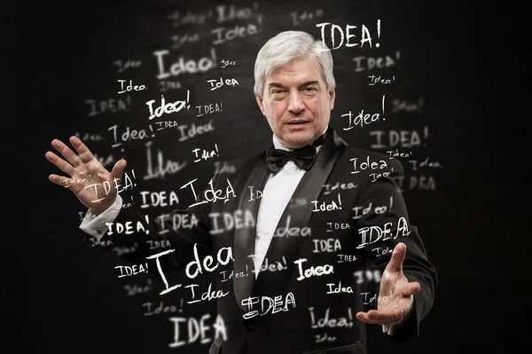 Ideia conceito. maduro homem de negócios de pé no preto fundo — Fotografia de Stock