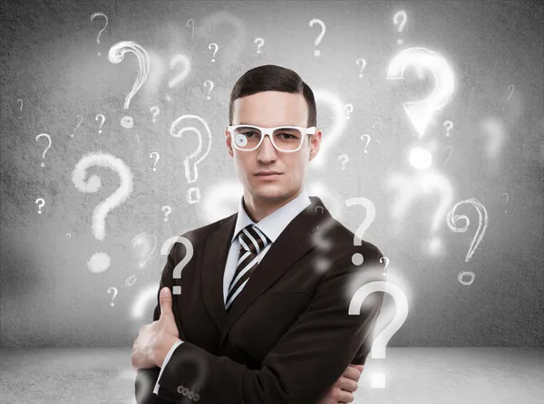 Handsome business man with question marks above his head — Stock Photo, Image