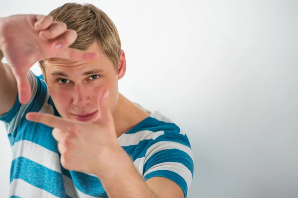 Retrato de joven europeo caucásico sonriente haciendo marco con el dedo — Foto de Stock