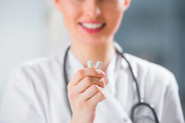 Joven dentista doctora sosteniendo goma de mascar y sonriendo . —  Fotos de Stock