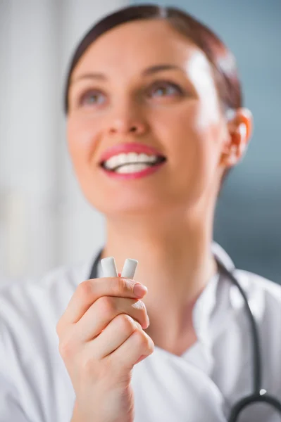 Νεαρή γυναίκα οδοντίατρος γιατρός κρατώντας τσίχλες και χαμογελαστός. — Φωτογραφία Αρχείου