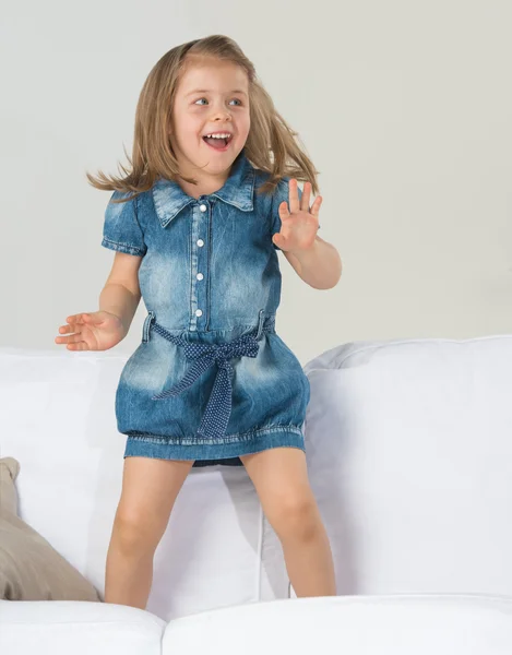 Adorable little girl jumping at home on sofa — Stock Photo, Image