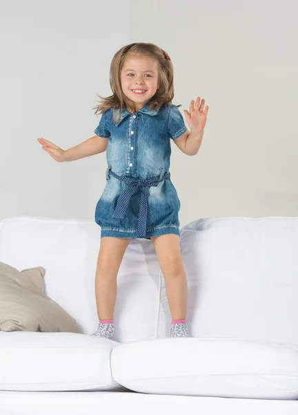 Adorable little girl jumping at home on sofa — Stock Photo, Image