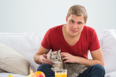 adam ve evde bir kedi. yakışıklı erkek tekir kedi onun Divan sarılma