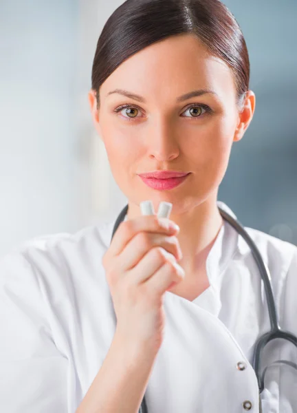 Junge Zahnärztin hält Kaugummi in der Hand und lächelt. — Stockfoto