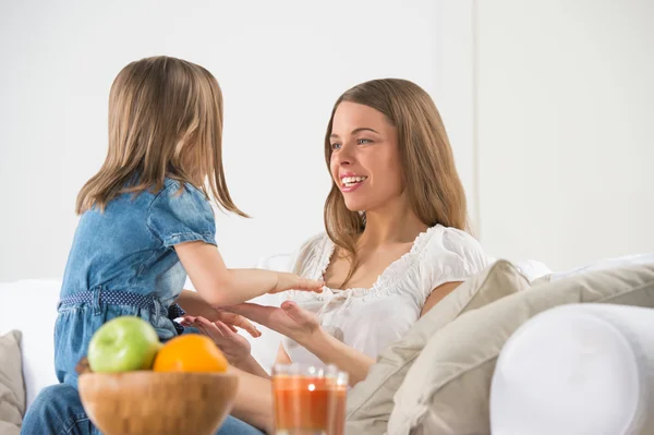 Happy smiling mother and daughter playing together on sofa — Stock Photo, Image