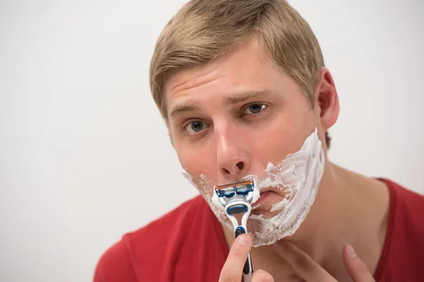 Feliz jovem adulto homem barbear seu rosto sobre fundo branco — Fotografia de Stock