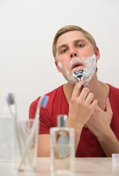 Young man shaving in the bath. — Stock Photo, Image