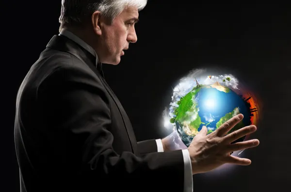 Senior business man holding planet in his arms and controlling it — Stock Photo, Image