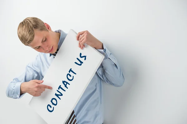 Schöner Geschäftsmann zeigt "Kontaktieren Sie uns" Text auf einer Plakatwand — Stockfoto