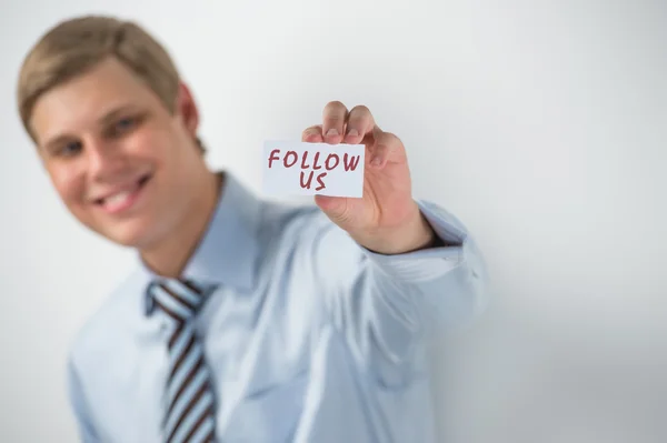 Handsome businessman showing "follow us" text on a business card — Stock Photo, Image